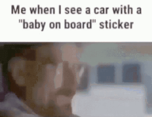 a man is sitting in a car with a baby on board sticker on the back of the car .