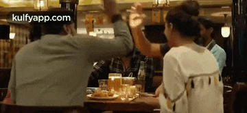 a group of people are sitting at a table in a restaurant having a drink .
