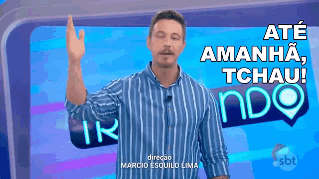 a man in a blue striped shirt is standing in front of a sign that says até amanha tchau