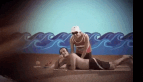 a man is laying on a beach while a woman massages him .