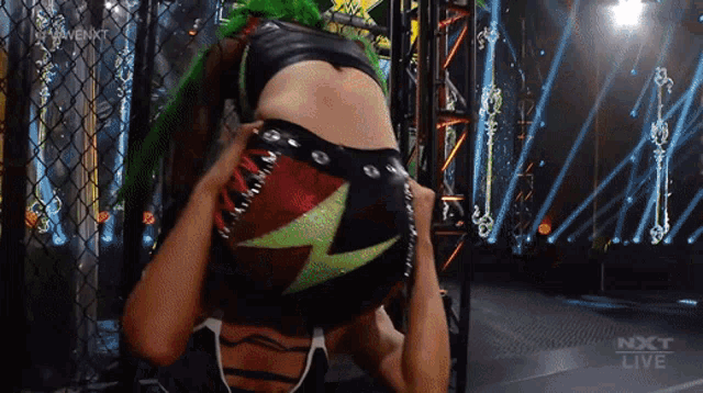 a female wrestler with green hair is being pinned down by another wrestler on a nxt live broadcast