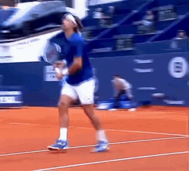 a man in a blue shirt is playing tennis on a court
