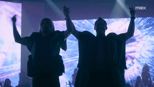 two men are dancing in front of a large screen that says mix