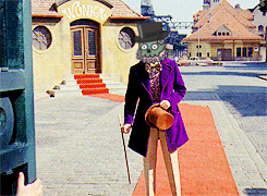 a man in a purple coat and top hat stands in front of a building that says wonkee