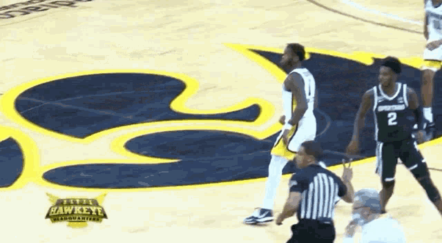 a basketball game is being played on a court that has the hawkeye logo on it