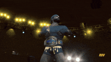 a man in a yellow jacket is wearing a wrestling belt with the word rov on the bottom