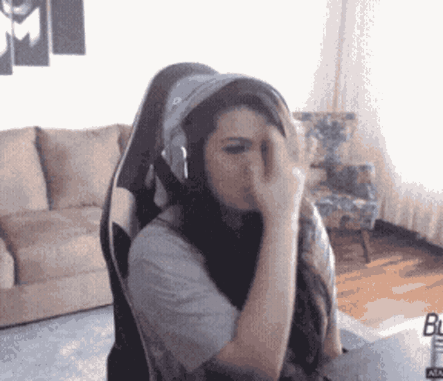 a woman wearing headphones and a hat is sitting in a living room