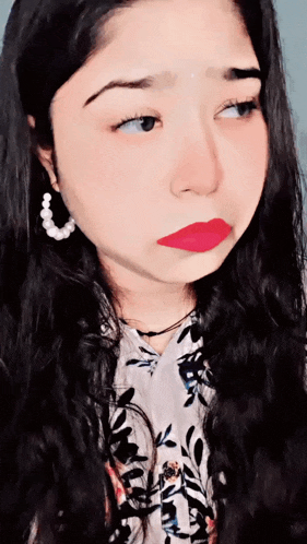 a close up of a woman 's face with red lips and pearl earrings
