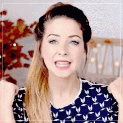 a woman in a blue and white shirt is making a funny face while sitting in front of a christmas tree .