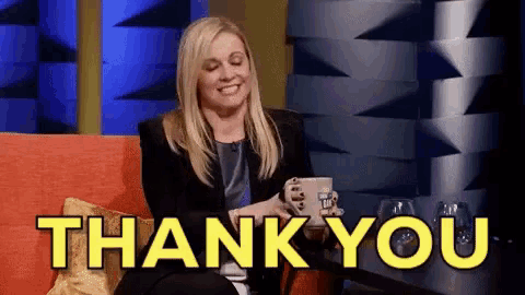 a woman is sitting on a couch holding a cup of coffee and saying thank you