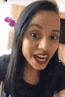 a woman with long black hair is making a funny face while looking at the camera .