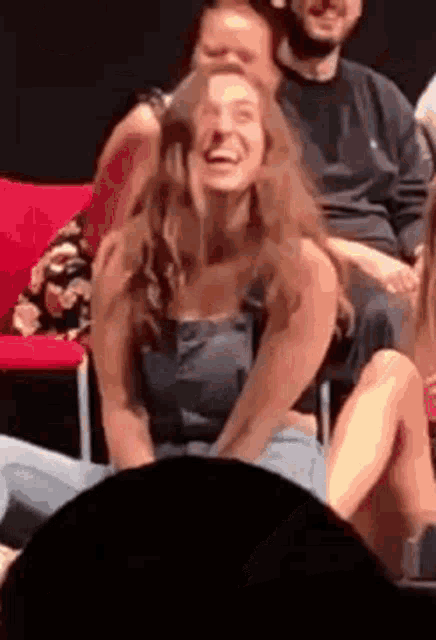 a woman is laughing while sitting in a crowd of people in a theater .