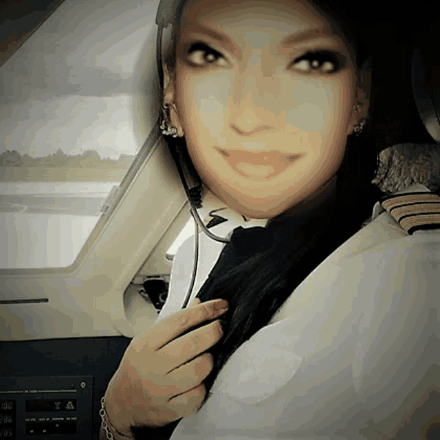 a woman wearing a headset is sitting in the cockpit of an airplane with a thermometer displayed on the dashboard