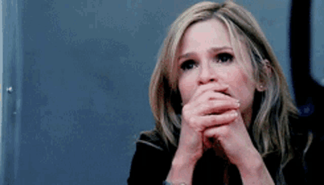 a woman covering her mouth with her hands while looking at something