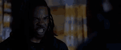 a man with dreadlocks is screaming in the dark .