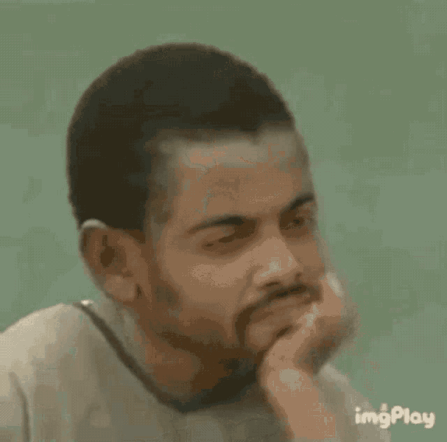 a man with a beard is sitting on the floor with his eyes closed .