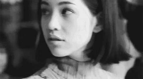 a black and white photo of a woman 's face looking at the camera .