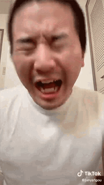 a man is making a funny face with his mouth open and his eyes closed .