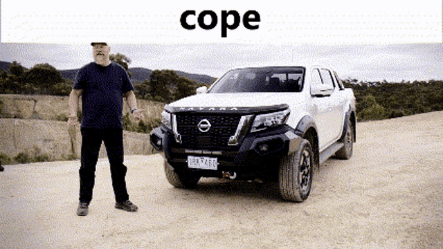 a man stands in front of a white nissan pickup truck