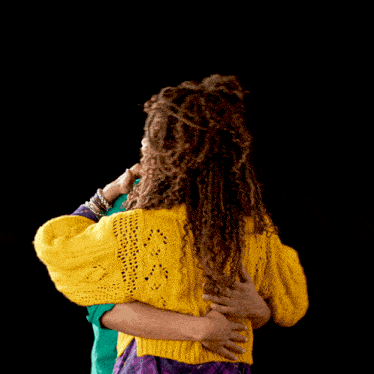 a man in a green shirt and a woman in a yellow sweater are hugging each other