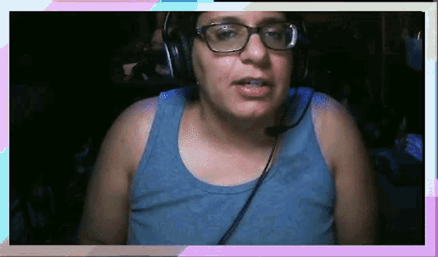 a woman wearing glasses and a blue tank top is talking into a microphone