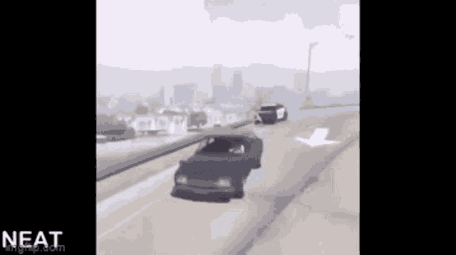 a black car is driving down a highway next to a white car .