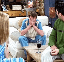 a man sits on a couch with his hands over his face