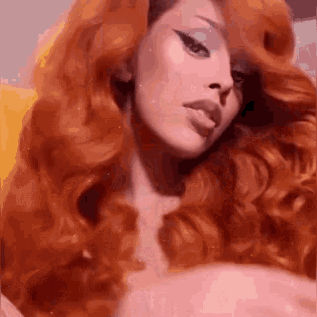 a woman with long red hair and a shaved head is wearing a pink wig .