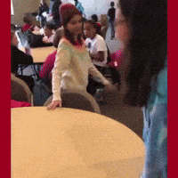 a girl in a white sweater and a red hat is standing in front of a table