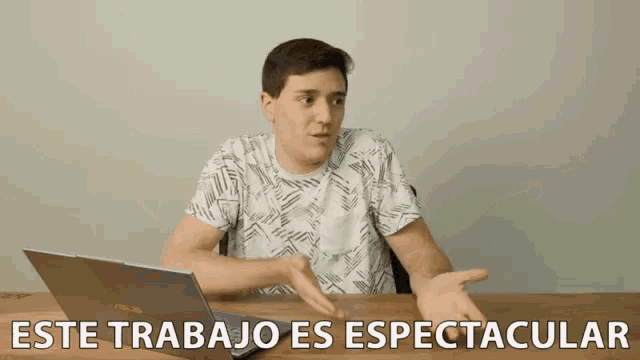 a man sitting at a table with a laptop and the words este trabajo es espectacular on the bottom