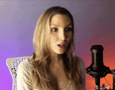 a woman sitting in front of a microphone with a purple background