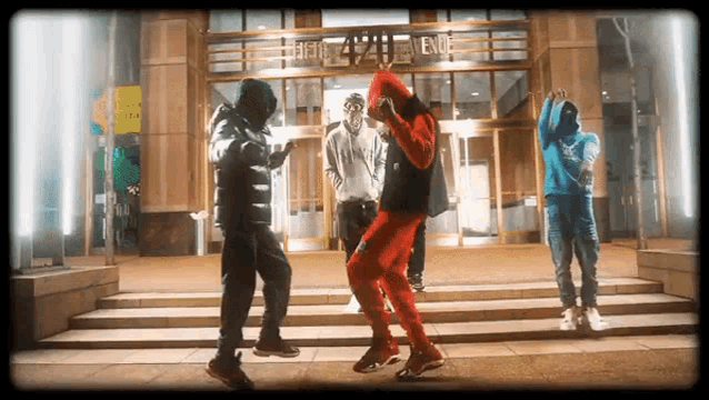 a group of young men are dancing in front of a building at night .