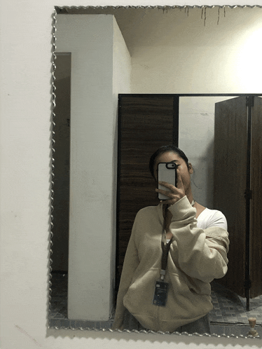 a woman taking a selfie in front of a mirror