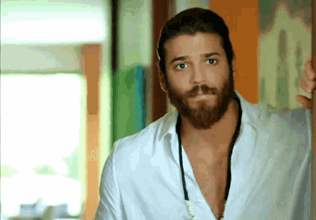 a man with a beard wearing a white shirt and a necklace