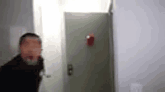 a blurry picture of a man standing next to a door .