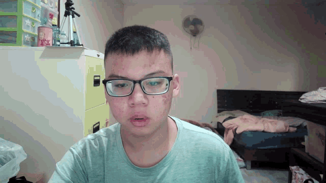 a man wearing glasses and a blue shirt looks at the camera