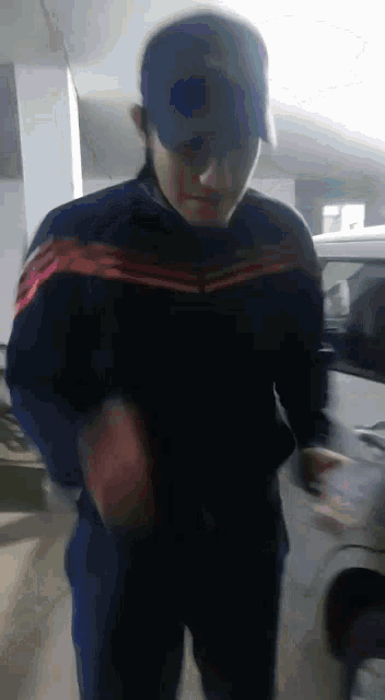 a man wearing a blue hat and a blue jacket is standing in a garage .