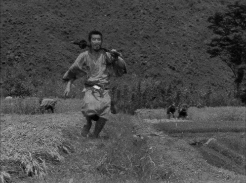 a black and white photo of a man holding a sword and smiling
