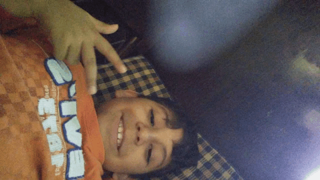 a young boy wearing an orange shirt that says ' smm ' on it