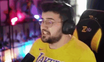 a man wearing headphones and a lakers shirt is sitting in a chair .