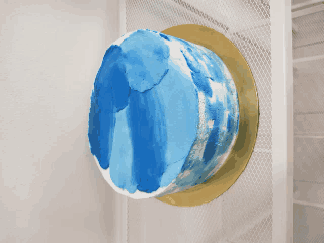 a blue and white cake is sitting on a gold tray
