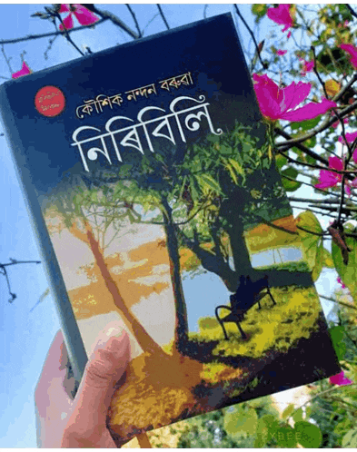 a person is holding a book in front of a tree