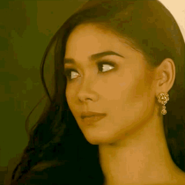 a close up of a woman 's face with gold earrings