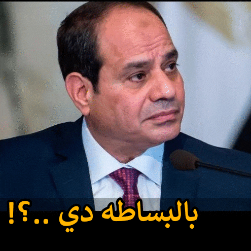 a man in a suit and tie stands in front of a microphone with arabic writing below him