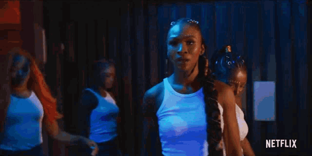 a group of women are standing next to each other in a dark room in front of a netflix logo .