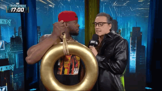 a man in a red hat is holding a gold ring in front of a man with glasses