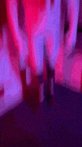 a blurry picture of a person standing in a room with pink and purple lights