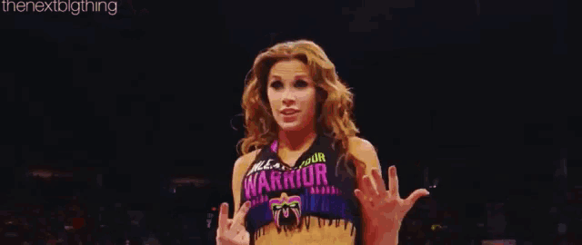 a woman wearing a warrior shirt is giving the middle finger .