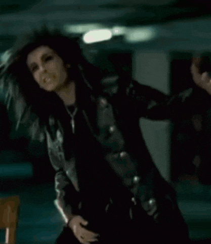 a woman in a leather jacket is standing in a dark room .
