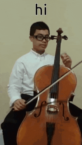 a young boy wearing glasses is playing a cello and says hi .